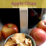 Air fryer in background, with 4 apples on a table. Apple chips in a bowl.