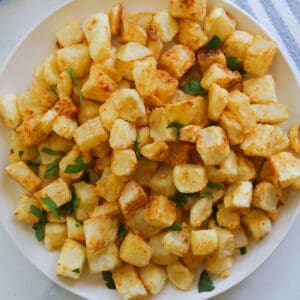 Plate of Closeup crispy cut potato squares.