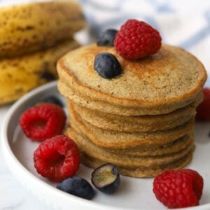 stack of small pancakes garnished with raspberries and blueberries