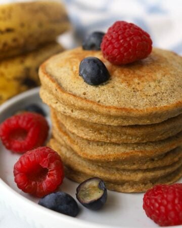 stack of small pancakes garnished with raspberries and blueberries