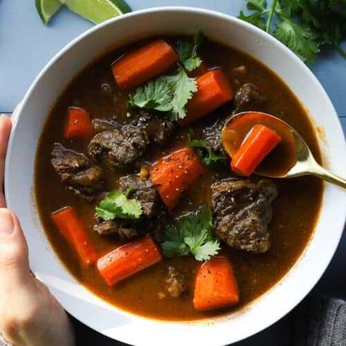 Bowl of beef stew with carrots. Garnished with cilantro.