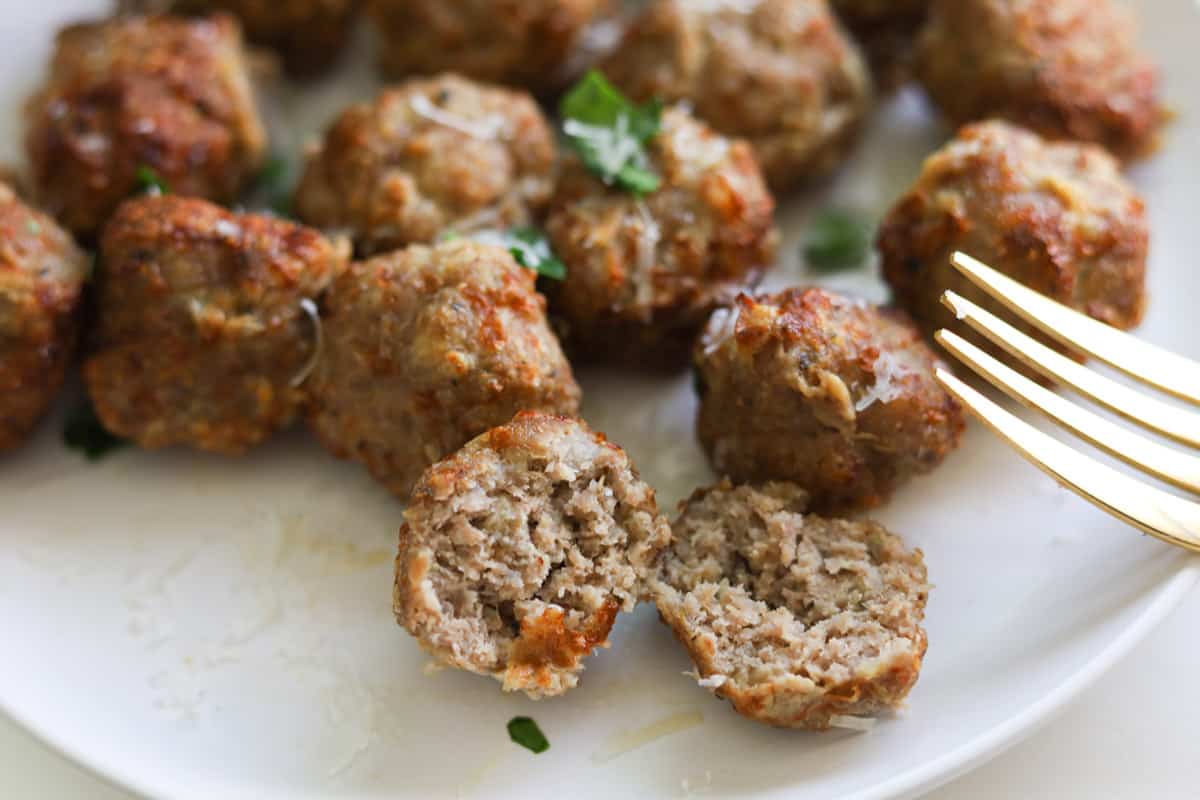 Close up of golden brown meatballs with one cut in haf.