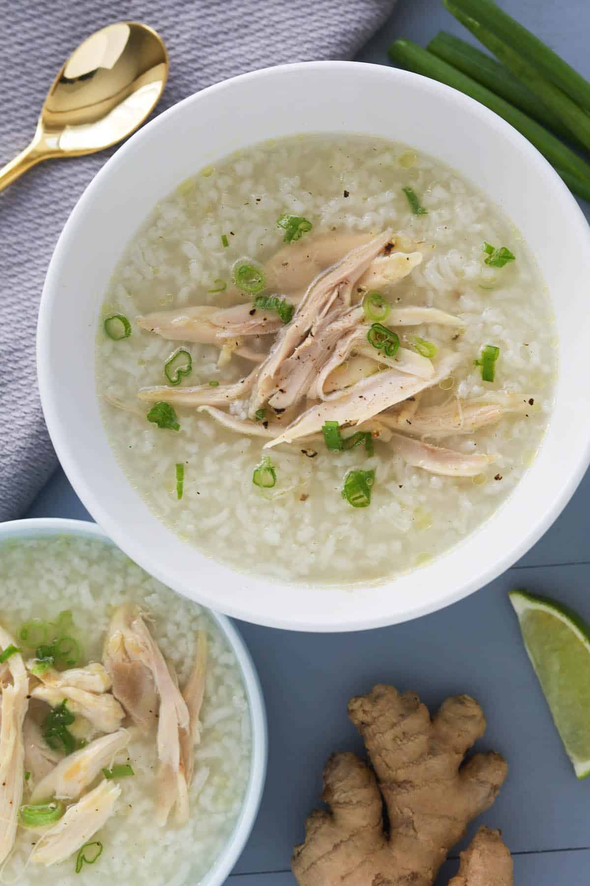 Two bowls of rice porridge with shredded chicken, garnished with green onions.