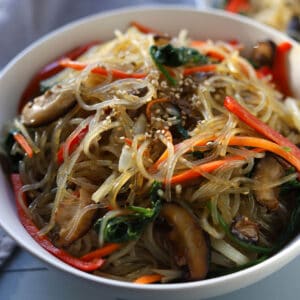 bowl of sweet potato noodles mixed with variety of vegetables and beef.