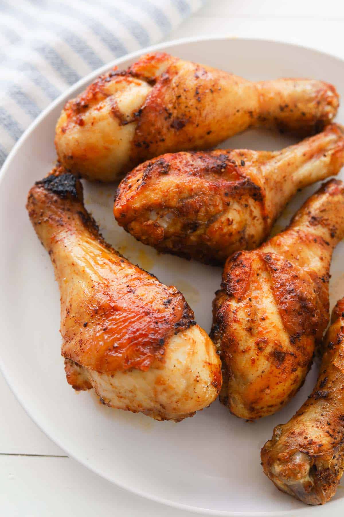 Closeup of cooked chicken drumsticks on a plate.