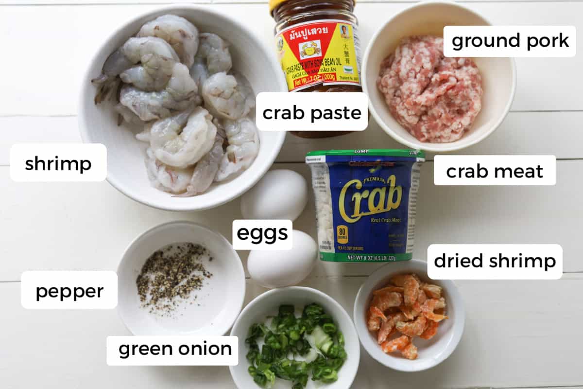 Ingredients on a table; green onion, ground pepper, dried shrimp, shrimp, eggs, crab meat, crab paste and ground pork.