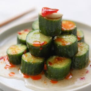 Closeup image of thickly sliced cucumbers on a dish with sauce.
