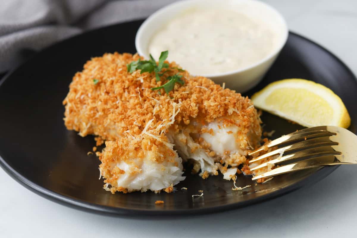 Closeup of flaked breaded cod fillet on a plate.
