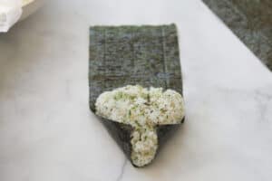 Folding end pieces of seaweed onto rice triangle.