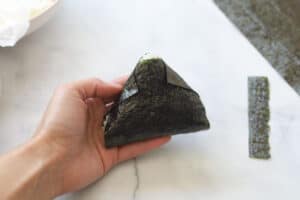 Completed folding of onigiri rice triangle.