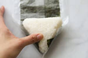 Folding seaweed paper onto rice triangle.