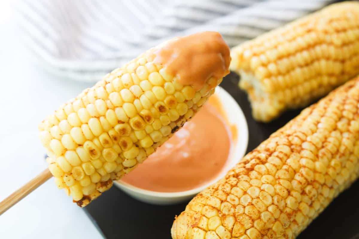 Closeup of half corn on the cob with dipping sauce.