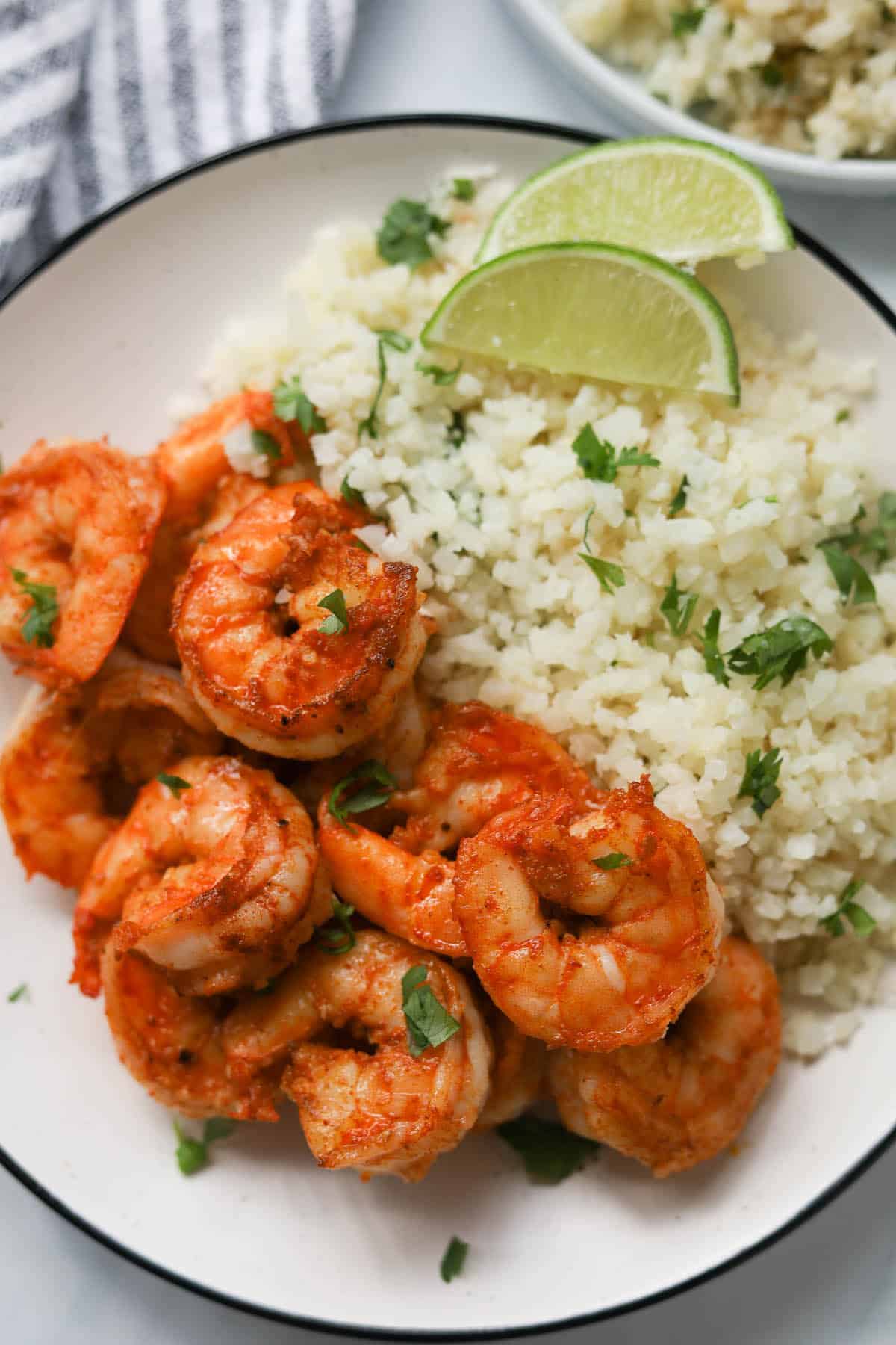 Cauliflower rice with jumbo shrimp, garnished with cilantro on a plate.