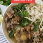 Bowl of rice noodle soup with meat and herbs.