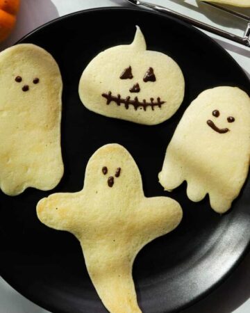 Ghost and pumpkin shaped pancakes on a plate.