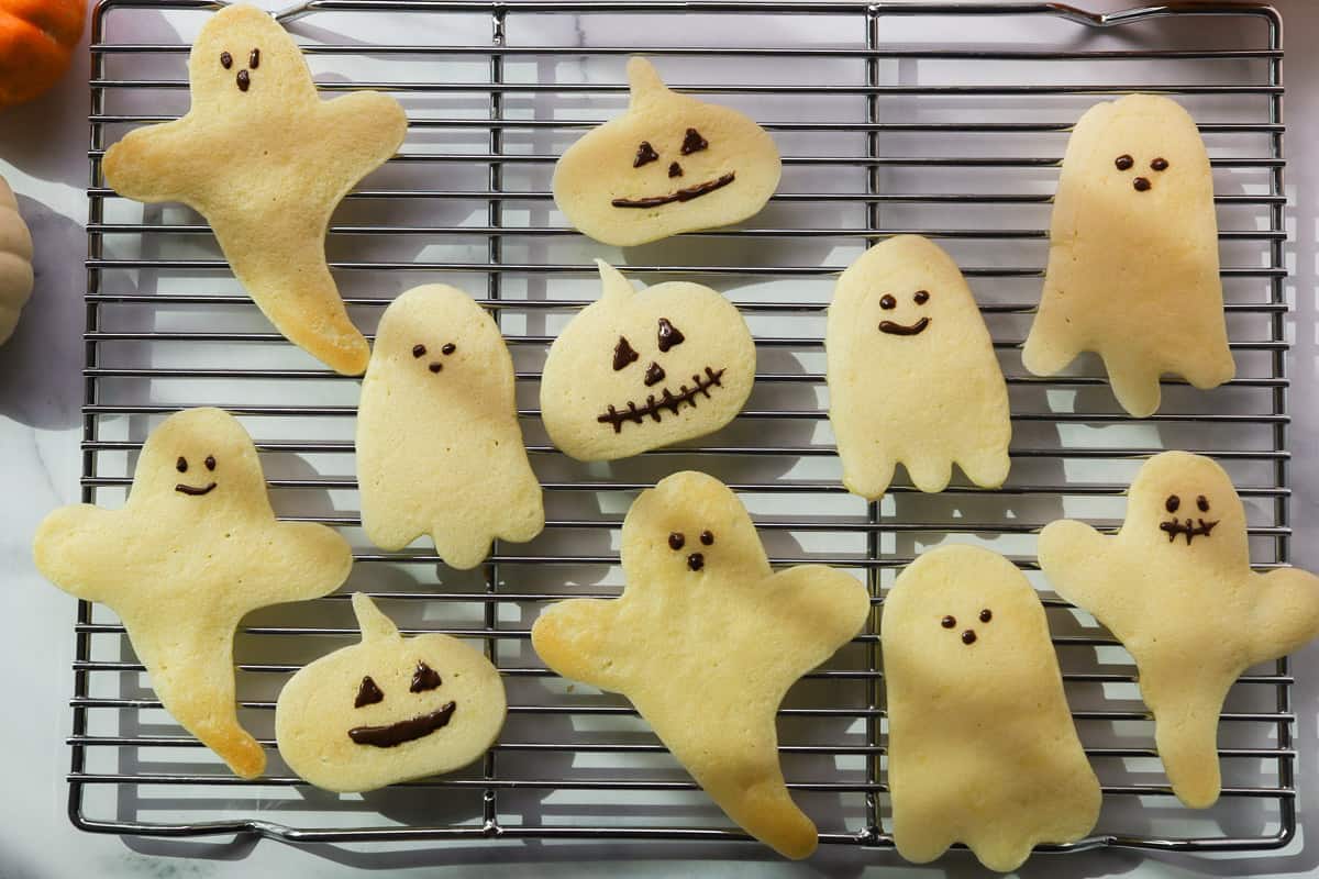 Pumpkin and ghost shaped pancakes on a baking rack.