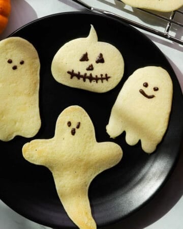 Ghost and pumpkin shaped pancakes on a plate.