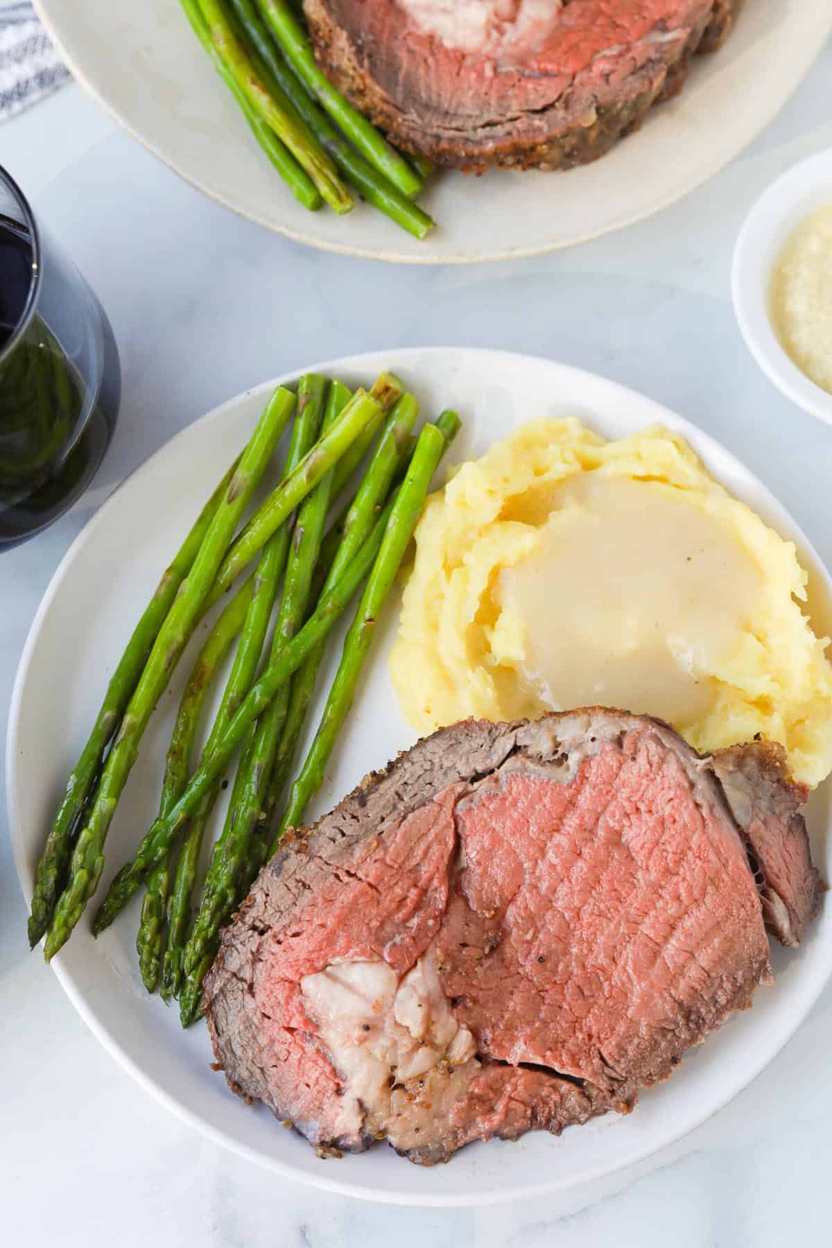 Prime rib roast dinner with mashed potatoes and asparagus.