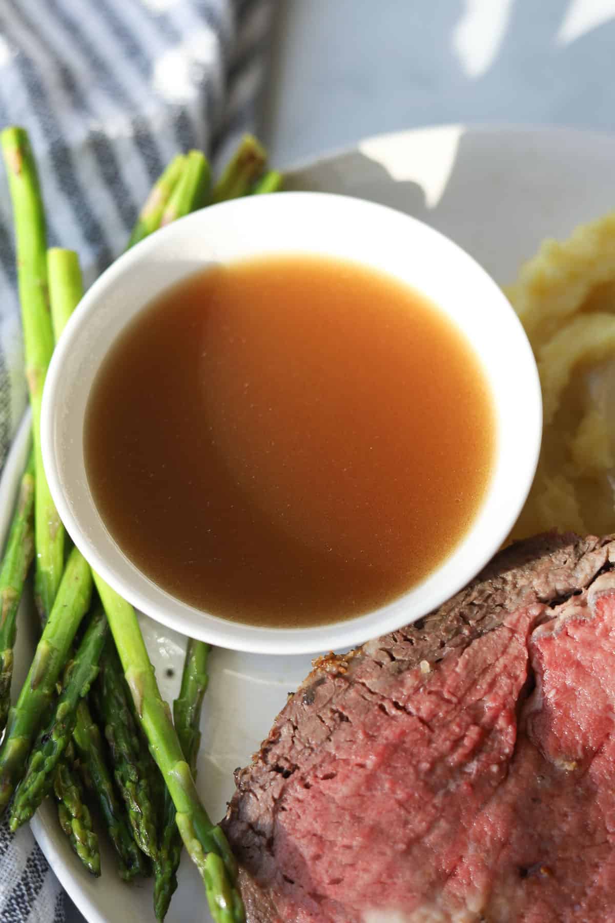 Bowl of au jus on plate.