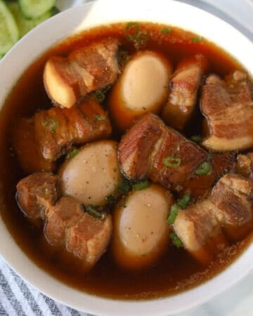 Bowl with pork belly and eggs in sauce.