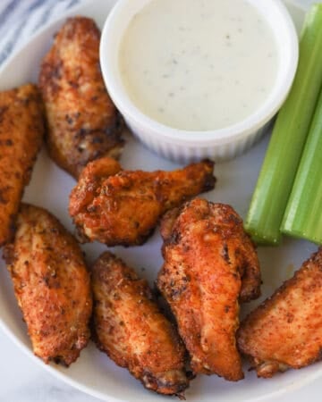 Plate of chicken wings with celery and dip.
