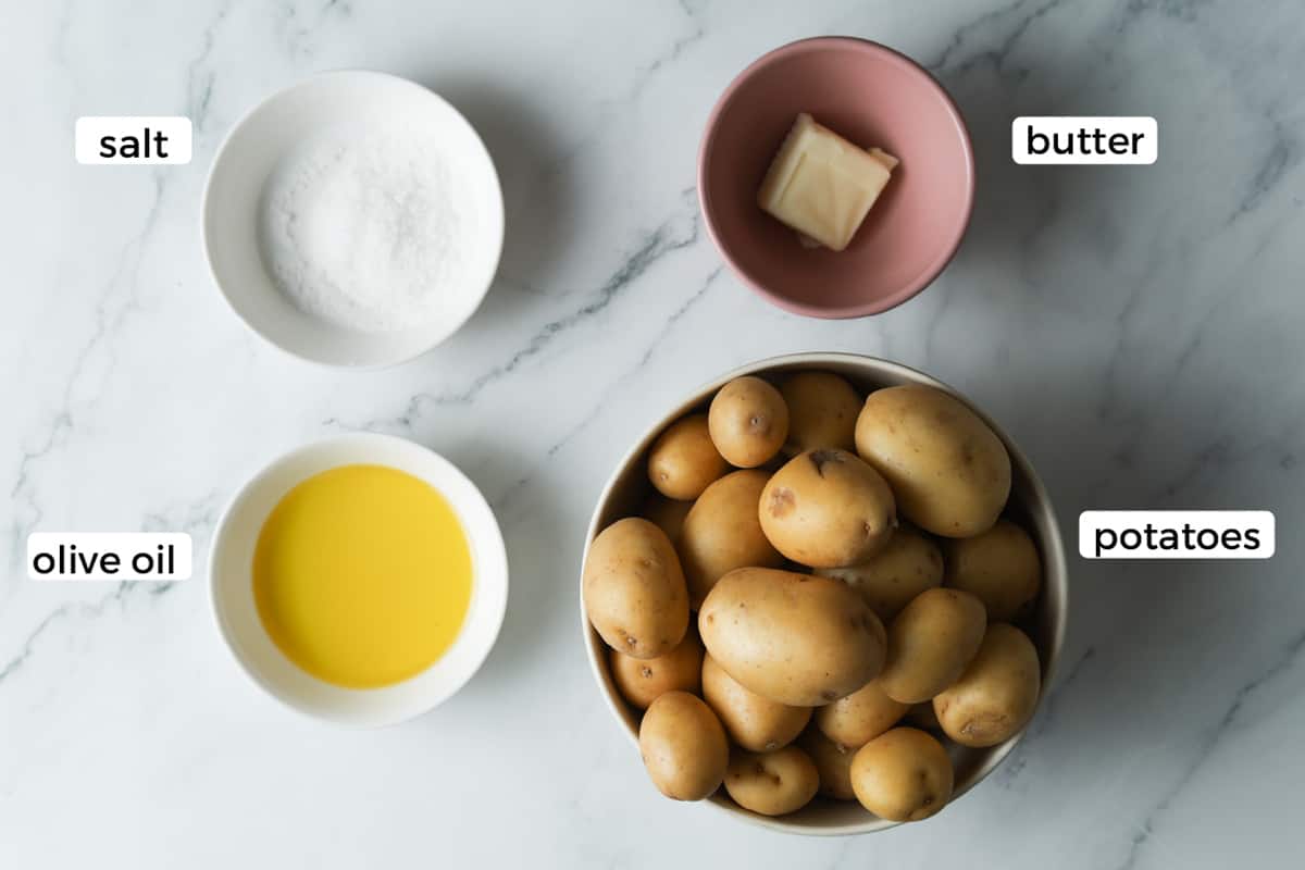 Ingredients in bowls, salt, olive oil, butter and baby potatoes.