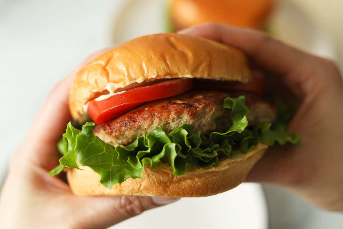 Hands holding a hamburger.