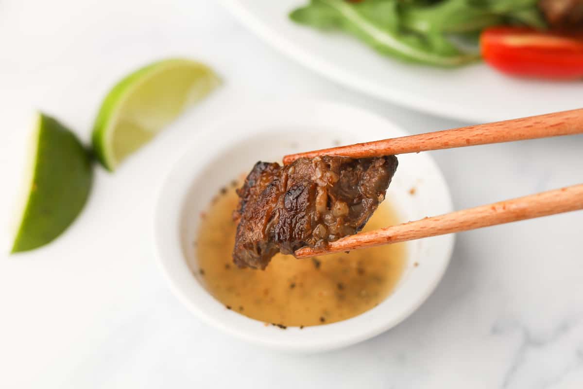Dipping piece of beef in lime sauce.