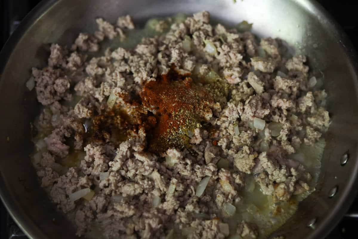 Ground meat with seasoning in a pan.