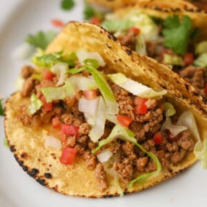 Taco with ground meat, lettuce and tomatoes.