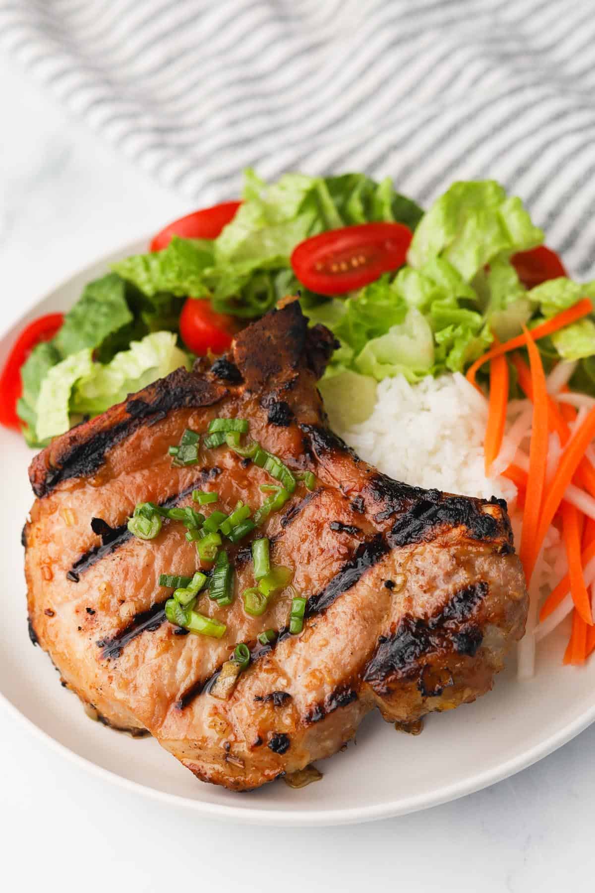 Grilled pork chop with rice and side of salad.