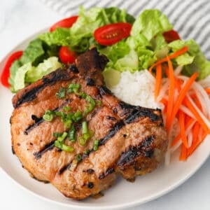 Grilled pork chop with rice and side of vegetables.