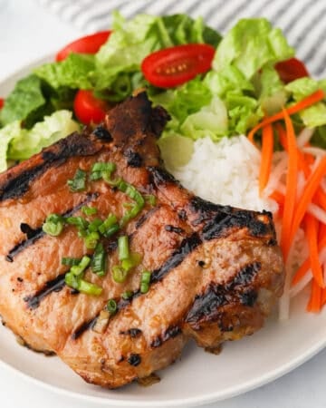 Grilled pork chop with rice and side of vegetables.
