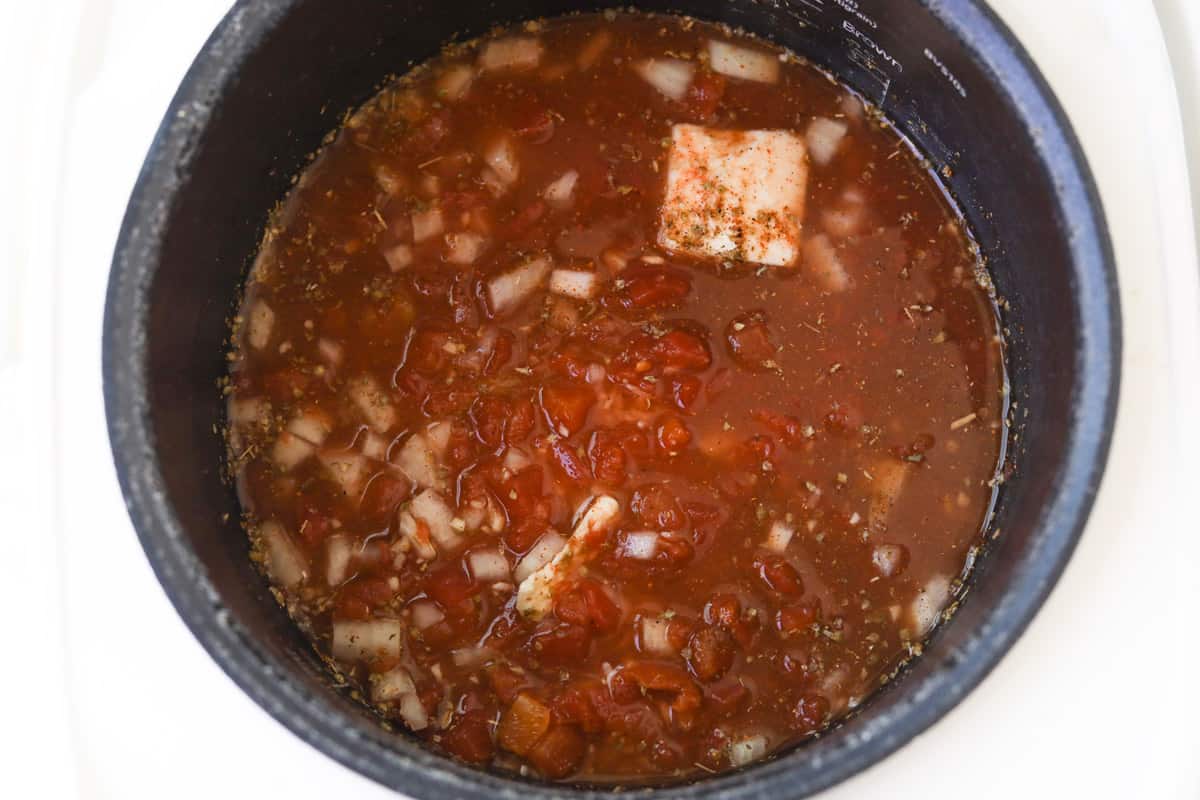 Tomato sauce, butter, onions, rice and seasoning in a pot.