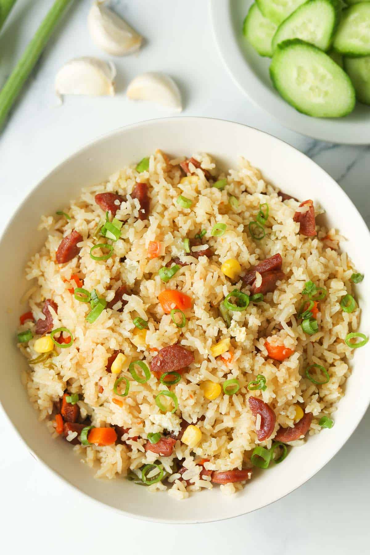 Bowl of fried rice with eggs, vegetables and sausage.