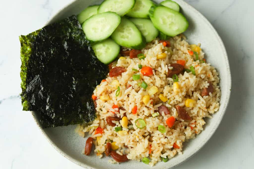 Fried rice with side of seaweed and cucumbers.