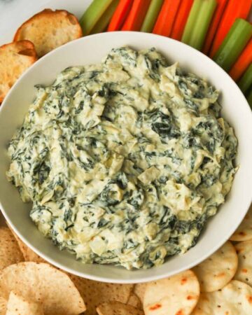 Spinach artichoke dip with chips and vegetables.