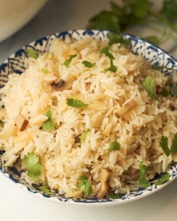 Rice pilaf with almonds and mushrooms in bowl.