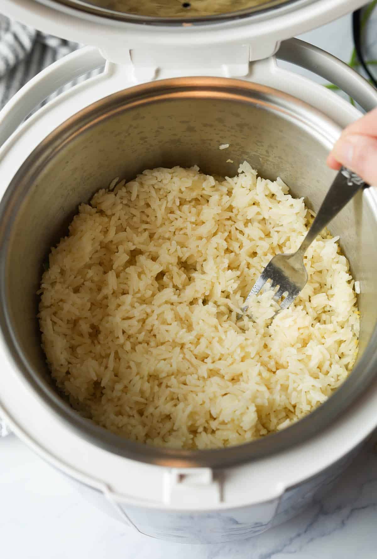 Fluffing rice with fork in rice cooker.