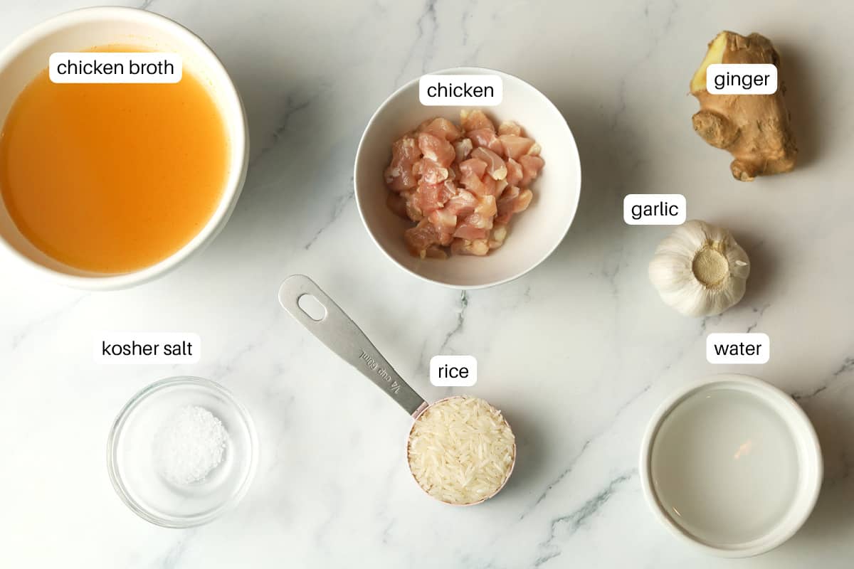 Ingredients on table; chicken broth, chicken, ginger, garlic, water, rice, salt.