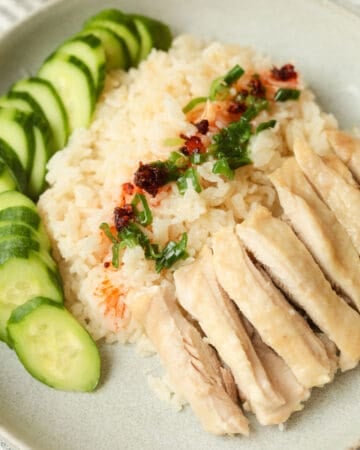 Plate with chicken and sliced chicken meat with side of sliced cucumbers.