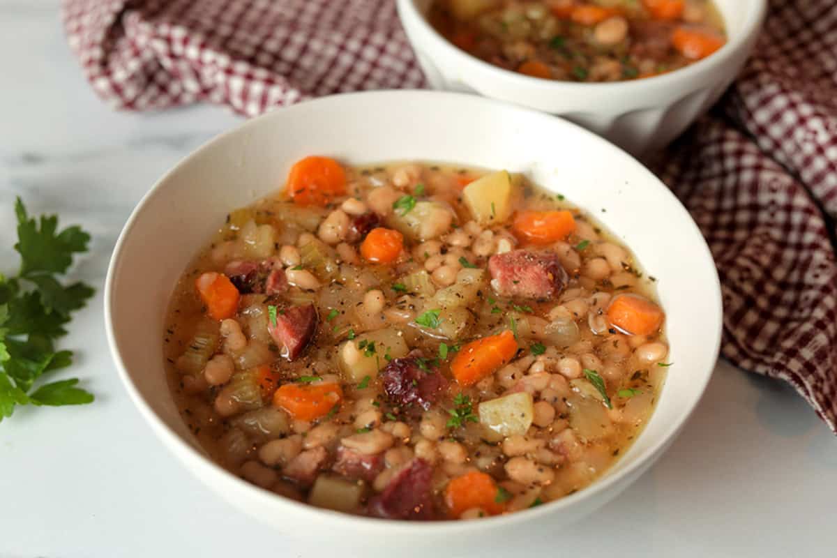 Bowl with white beans, diced ham, carrot and potatoes.