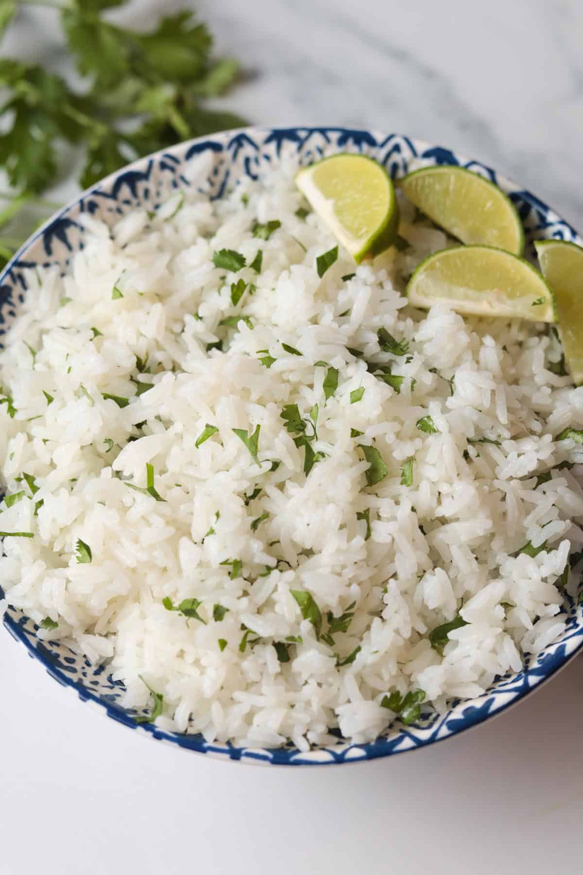 Cooked Jasmine rice with cilantro garnished with lime.