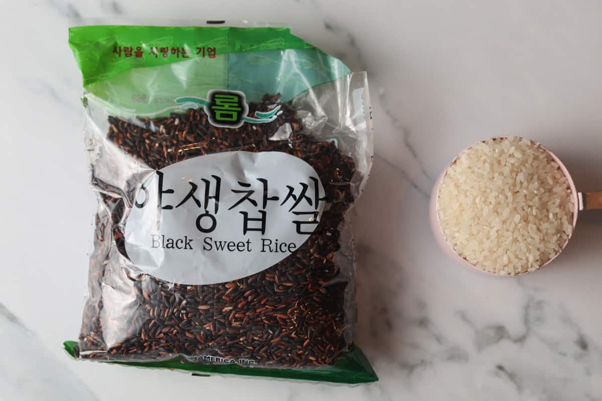 Bag of black sweet rice and white short grain rice in measuring cup.