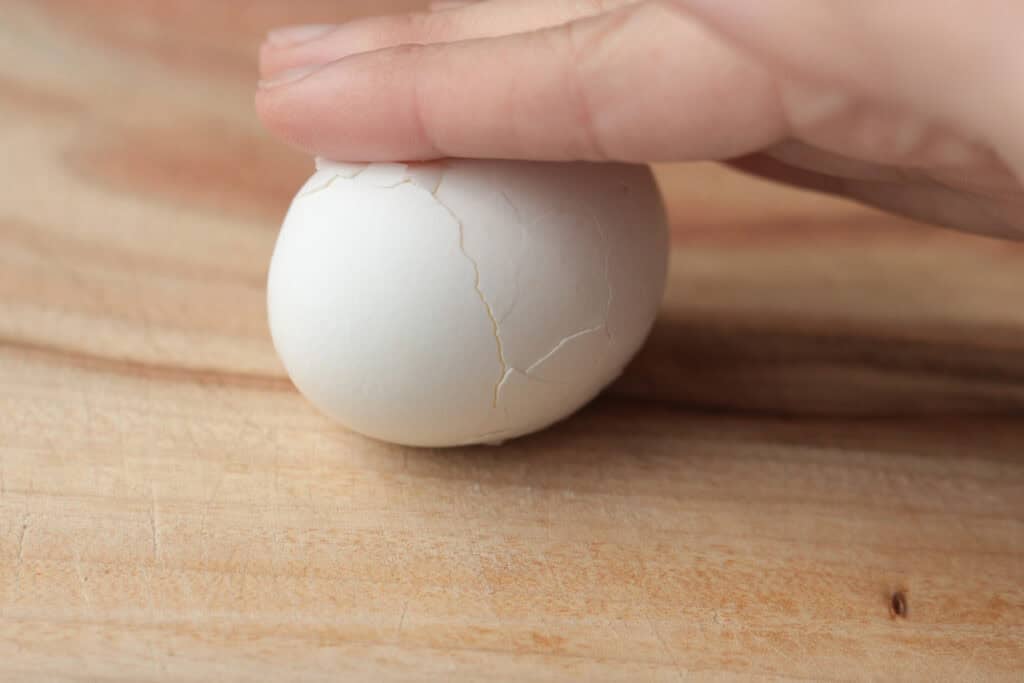 Rolling cracked egg on a board.