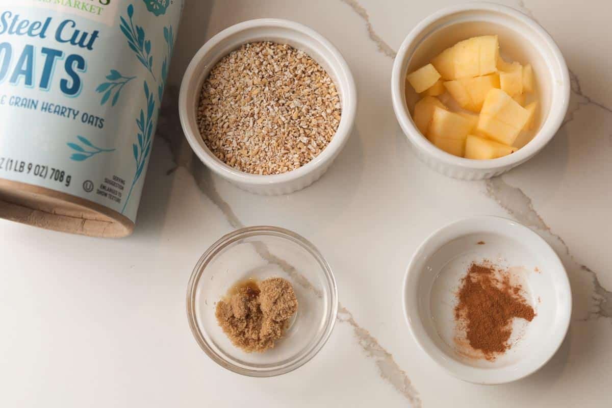 Ingredients on table, steelcut oats, brown sugar, cinnamon, cut apples.