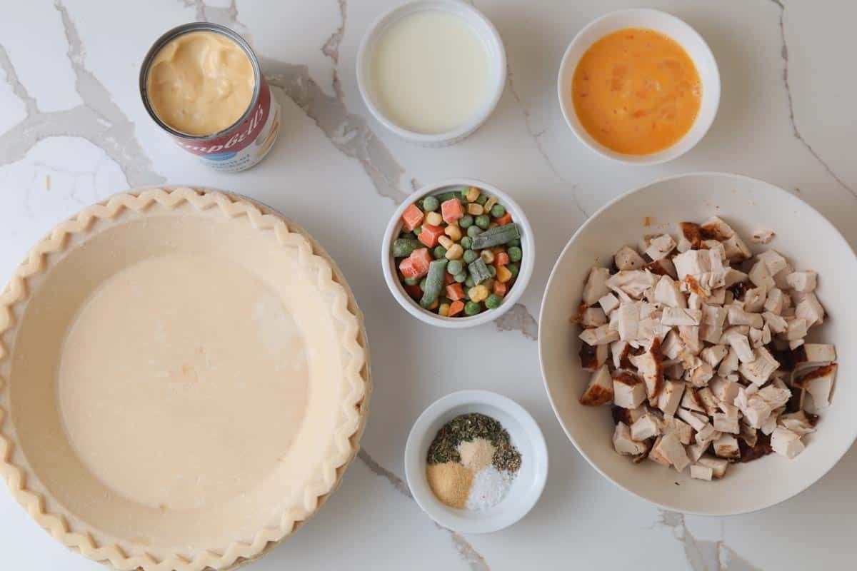 Ingredients for chicken pot pie; cream of chicken, pie crust, froze vegetables, seasoning, egg, milk, chicken