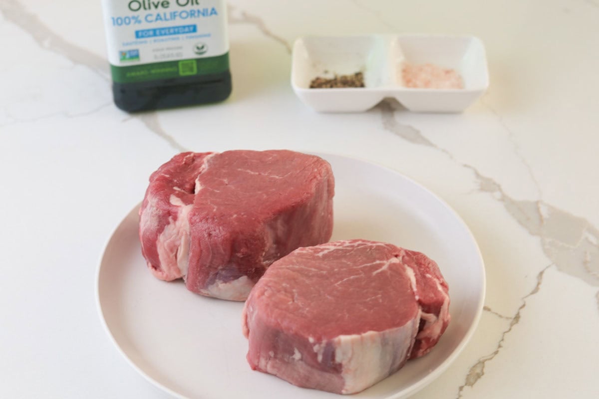 Two raw filet mignon, olive oil, salt and pepper.