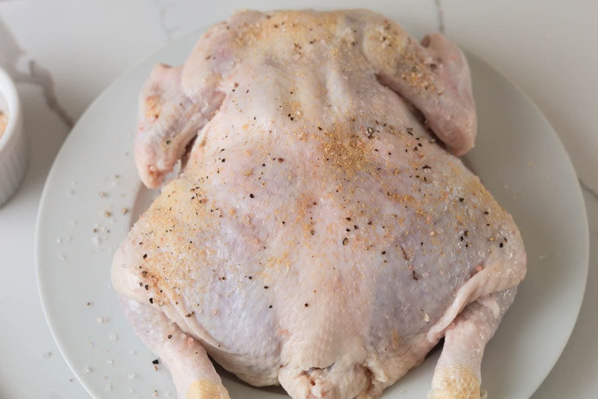 Seasoned whole raw chicken.