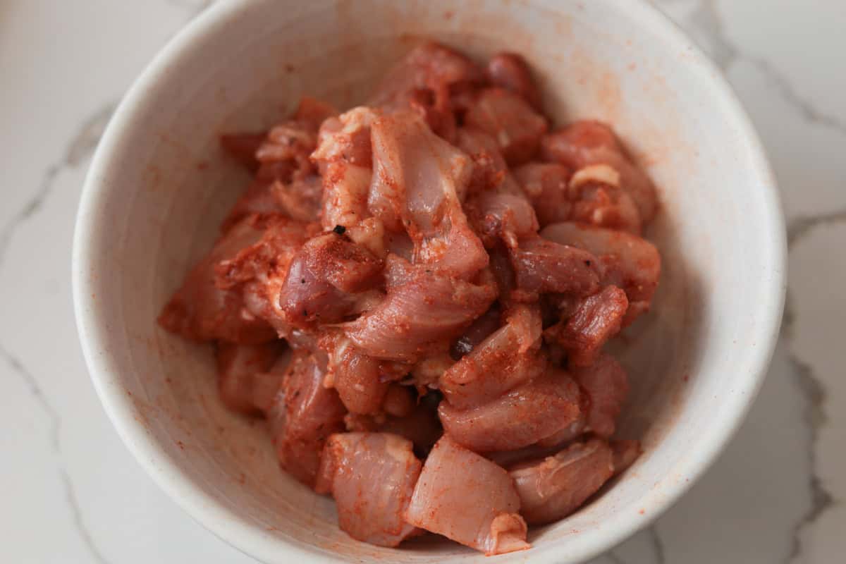Seasoned, uncooked chicken pieces in bowl.